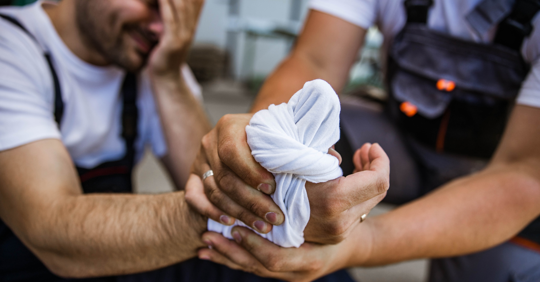 Man wrapping injured man's hand